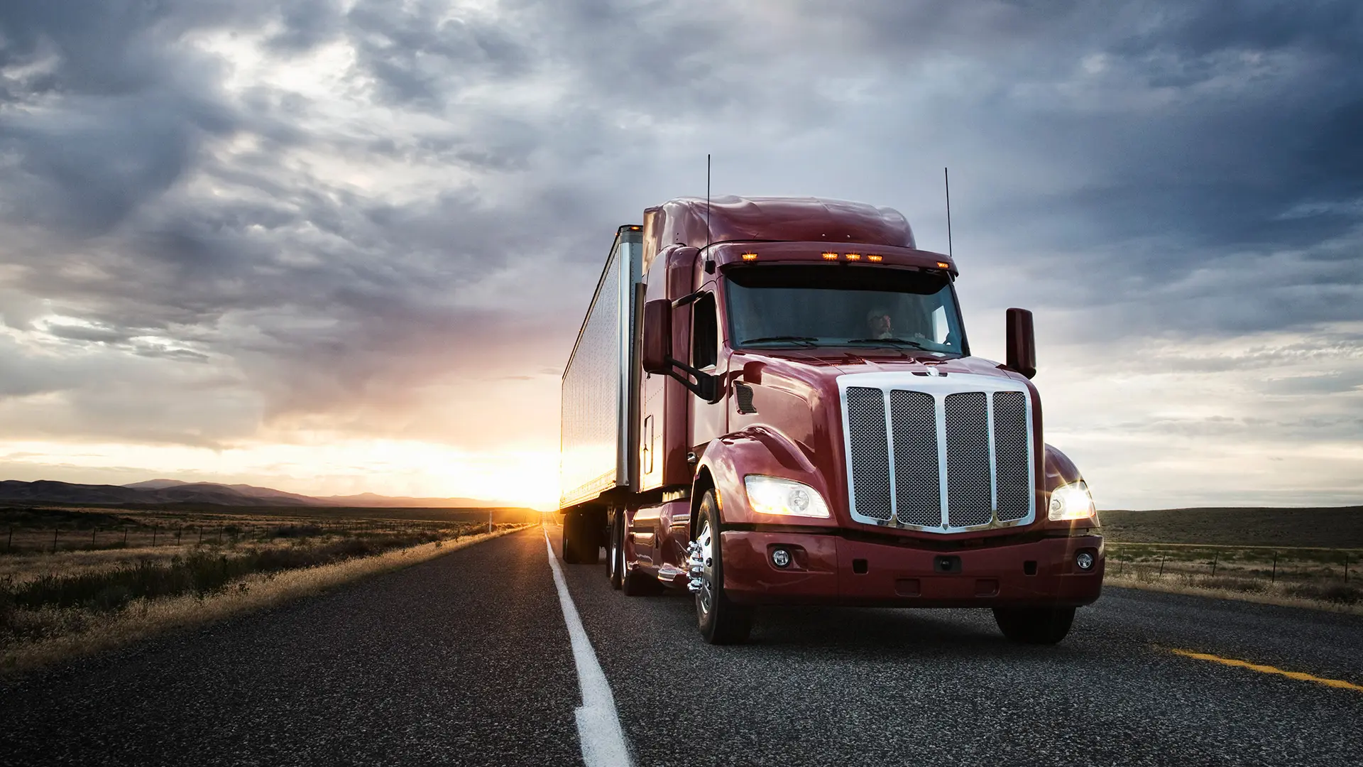 Semi truck driving on a highway at sunset
