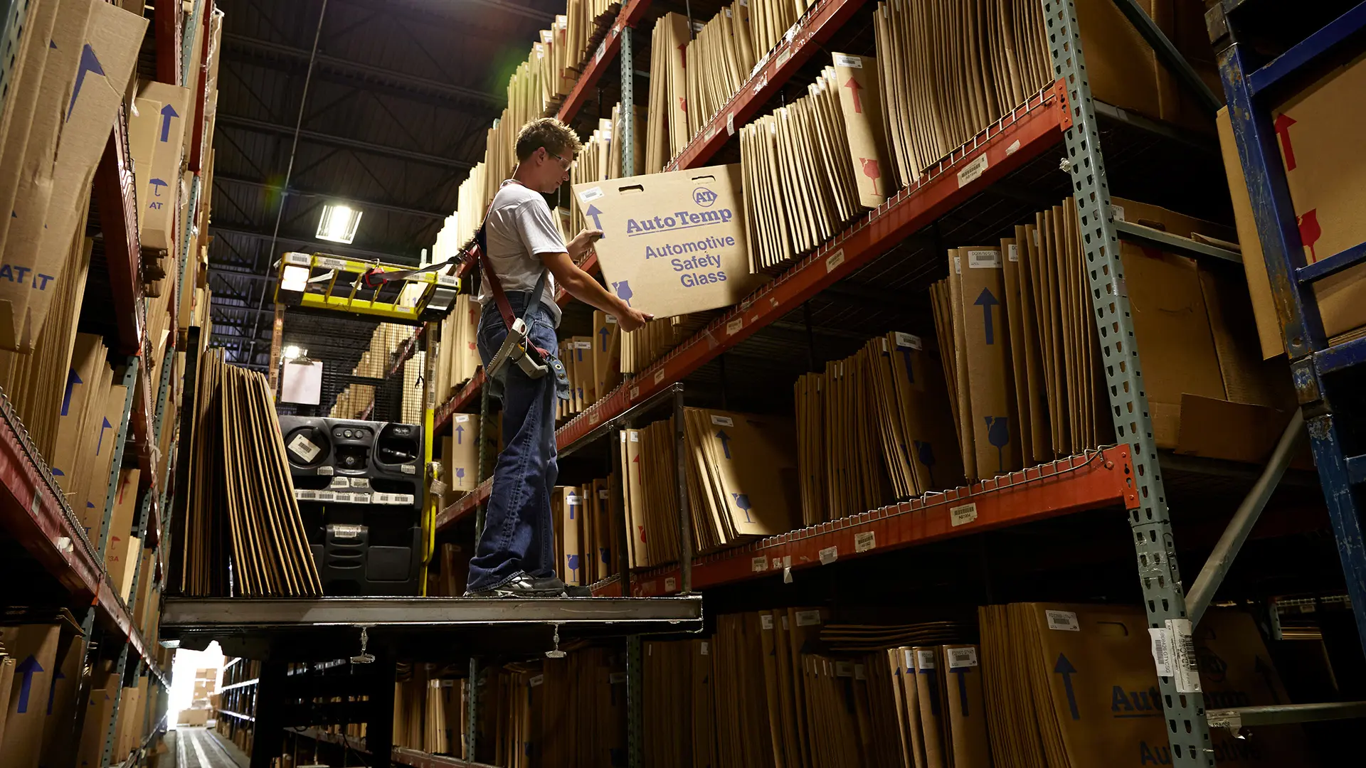 Warehouse worker picking boxed glass from high-bay shelving